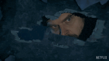a man looking through a hole in a wall with a netflix logo on the bottom