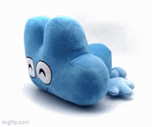 a blue stuffed animal with a face on it is laying on a white surface .