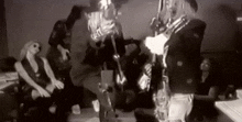 a black and white photo of a man playing a saxophone in front of a crowd .