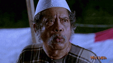 a man with a beard wearing a white hat and a plaid shirt with man laksa written on the bottom right