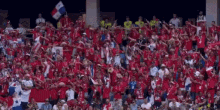 a crowd of people in red shirts are watching a soccer game .