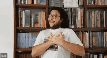 a man wearing glasses is standing in front of a bookshelf .
