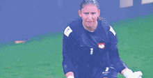 a female soccer player wearing a number 1 jersey is standing on the field .