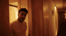 a man in a white shirt and tie is walking down a hallway