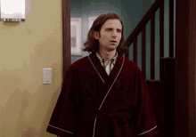 a man in a robe is standing in a doorway next to stairs