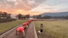 a group of people are doing push ups on a track in a field .