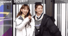 two young women are standing next to each other in front of a building that says security .