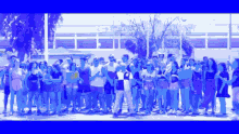 a large group of people are standing in a line and one of them is wearing a shirt with the letter o on it