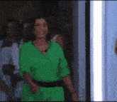 a woman in a green dress is smiling in front of a crowd of people .