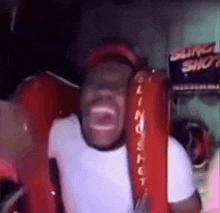 a man is screaming while riding a slingshot ride .