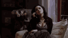 a woman is sitting on a couch talking on a phone