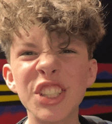 a young boy with curly hair making a funny face .