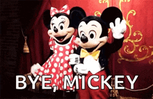 mickey mouse and minnie mouse are standing next to each other in front of a red curtain .