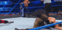 a man is laying on the ground in a wrestling ring while a referee stands behind him .