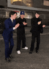 a man wearing a la hat is dancing with two other men in suits