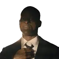 a man in a suit adjusts his tie with his hand