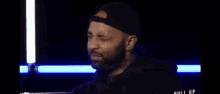 a man with a beard wearing a hat is making a funny face .