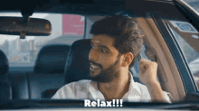a man with a beard is sitting in a car with the word relax written on the bottom
