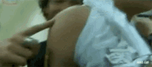 a man is getting a vaccine from a doctor and pointing at his arm .