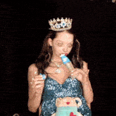 a woman with a crown on her head drinks from a bottle