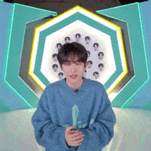 a young man wearing a blue sweater is standing in front of a green and yellow background .