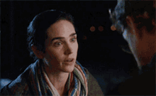 a woman wearing a scarf is talking to a man .