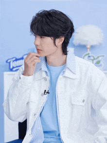 a man wearing a white jacket and a blue shirt is standing in front of a sign that says tem