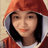 a close up of a woman wearing a red hooded jacket