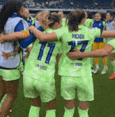 a group of female soccer players are hugging and one of them is wearing a number 17 jersey