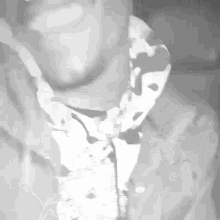 a black and white photo of a man wearing a camo shirt and tie .