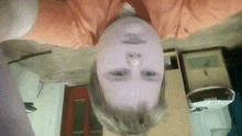 a person 's head is upside down and they are wearing a orange shirt
