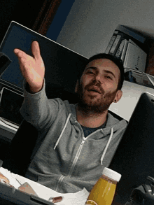 a man sitting at a desk with a bottle of orange juice on it