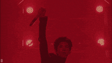 a man holding a microphone in front of a red background with the letter d visible