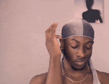 a man wearing a bandana on his head looks at the camera with his eyes closed