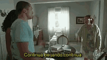 a man and a woman are standing in a living room with a sign that says continua beijando continua .