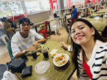 a man and a woman are sitting at a table in a restaurant eating food