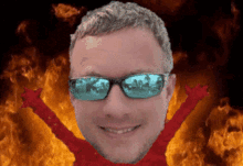 a man wearing sunglasses stands in front of a fire