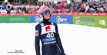 a skier wearing a number 40 jersey stands in front of a slovenia business sign