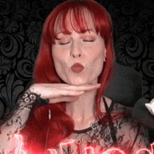 a woman with red hair is blowing a kiss in front of a sign that says ' i love you '