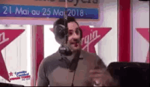 a man wearing headphones is talking into a microphone in front of a virgin sign
