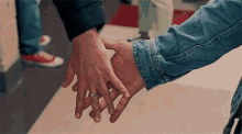 a man and a woman are holding hands and the woman is wearing a wedding ring .