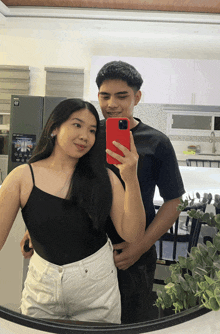 a man and a woman are taking a picture in front of a samsung refrigerator
