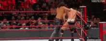 two wrestlers are fighting in a wrestling ring with a crowd watching .