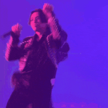a man is singing into a microphone in a purple light .