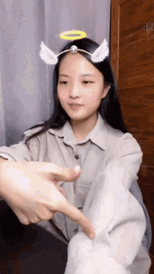 a girl with angel wings and a halo on her head is pointing