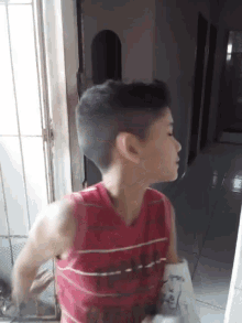 a young boy wearing a red tank top that says ' abercrombie ' on it