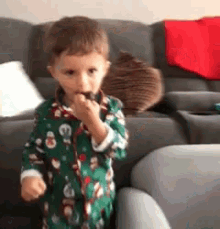 a little boy in a green pajamas is eating a chocolate