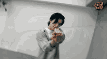 a man is making a heart shape with his hands in front of a white wall with chinese writing on it .