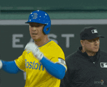 a baseball player wearing a blue helmet and a yellow jersey with the word boston on it