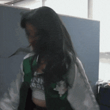 a woman wearing a green jacket and a white shirt that says ' i 'm a leaf ' on it
